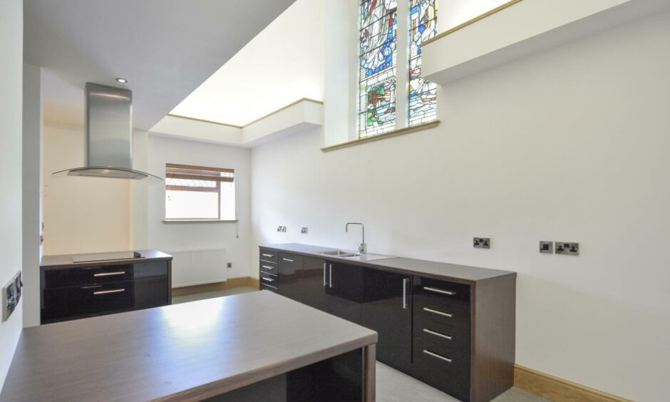 The modern kitchen sits beneath a stained glass window at Blairingone Church.