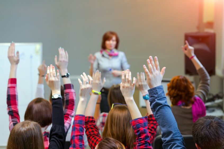 Students rising hands in a classroom - What the Stop Faculties campaign means for TEACHERS