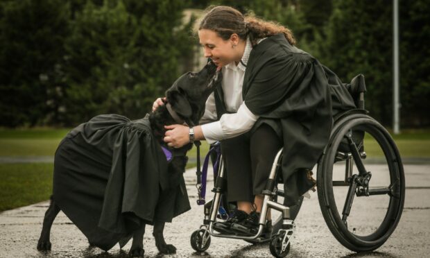 Megan McEvoy, 26, graduating with a masters in chemistry with her service dog, Flint.