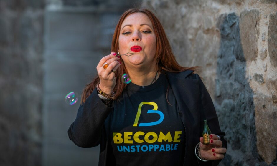 Lynn Erasmus wearing a Become Unstoppable tshirt blowing bubbles.