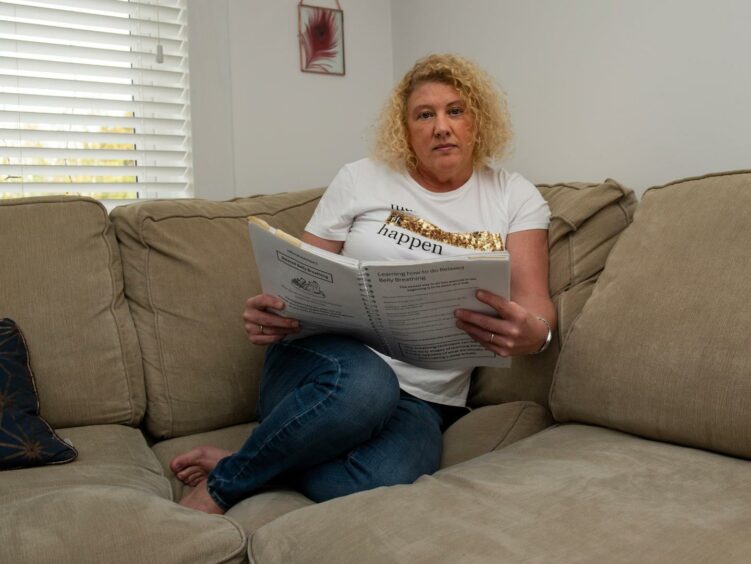 Adele Birkmyre, pictured sitting on a couch, is raising funds to help those with chronic pain.