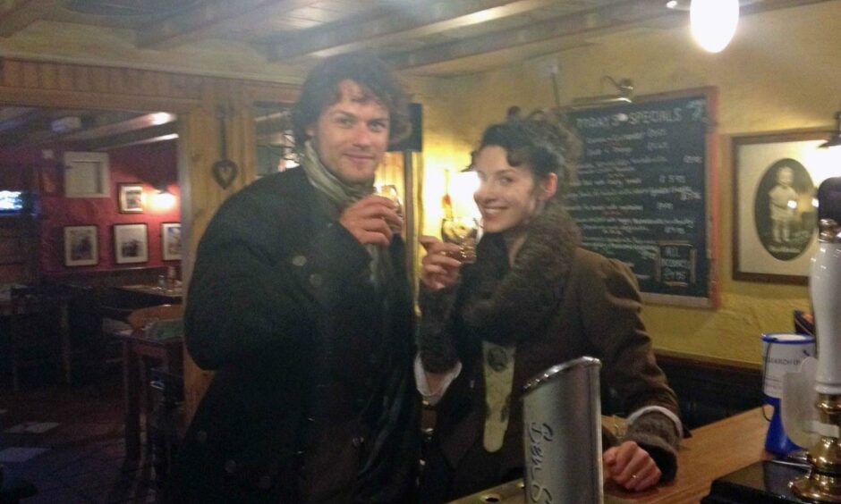 Sam Heughan and co-star Caitriona Balfe enjoy a drink in the Red Lion Inn in Culross during filming.
