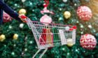 Trolley filled with gift bags in front of Christmas tree.