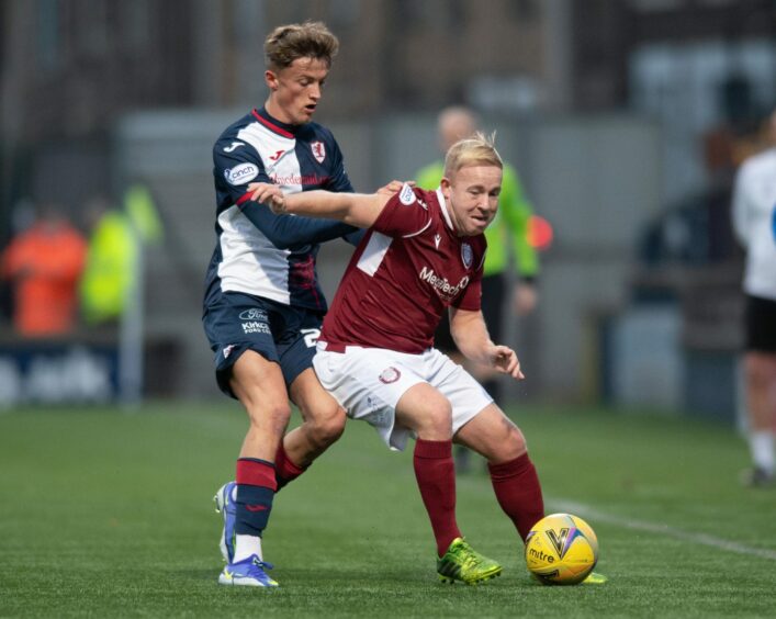 Nicky Low holds off attention from Raith Rovers' Ben Williamson.