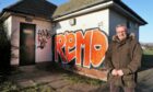 Councillor George McIrvine next to some of the graffiti.