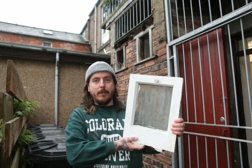Liam Thomson with the window the thieves took out.
