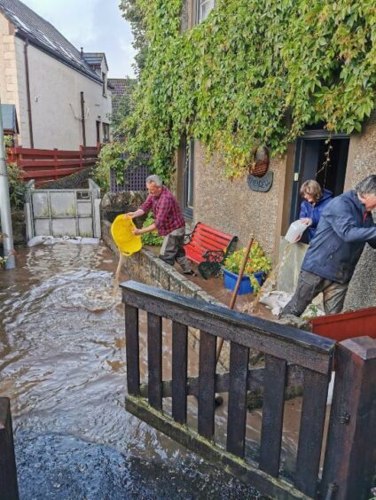 The Mullens and a neighbour racing to clear away flood water from their home.