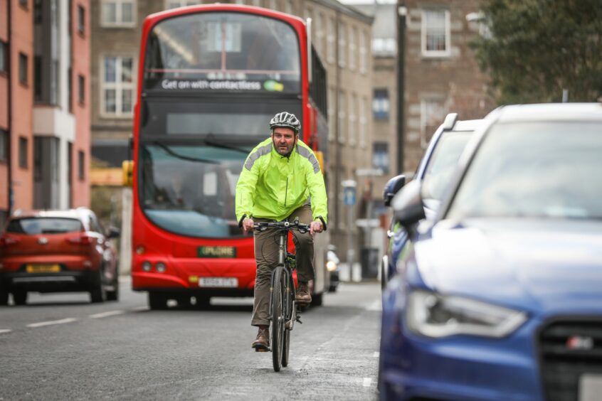 man on bike riding through busy Dundee city centre