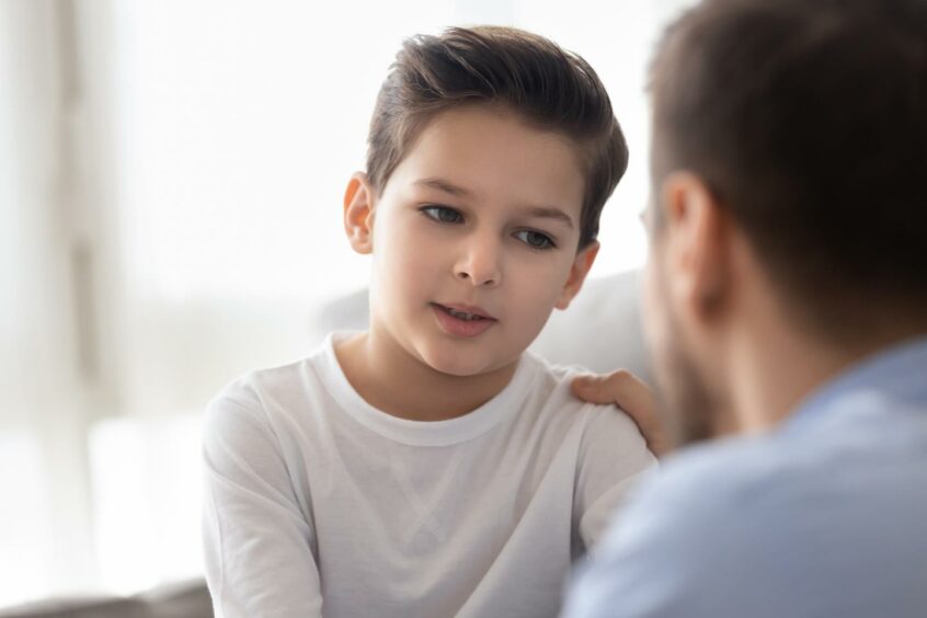 A young boy having a conversation with a parent about bullying