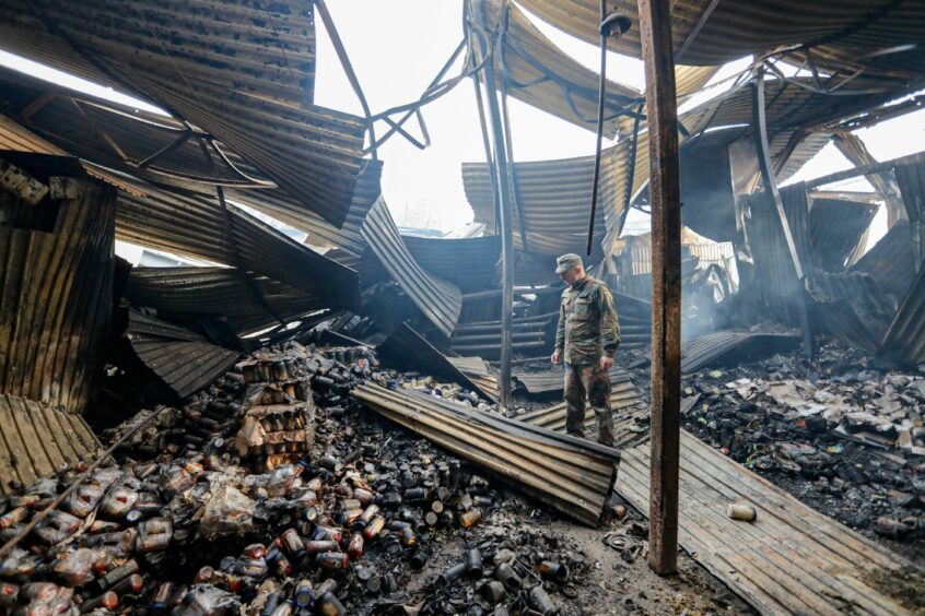 A Ukrainian solder surveying the wreckage of a major food warehouse near Kyiv. Picture Daniel Ceng Shou/Shutterstock.