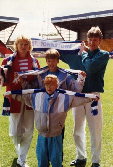 Sergei Baltacha with his family after signing for St Johnstone. They are each holding St Johnstone scarves on the McDiarmid Park pitch.