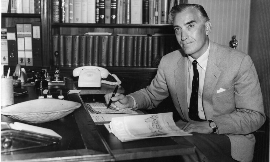 Neil Paterson, a talented footballer who later won an Oscar, sitting at his desk with pen in hand