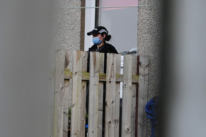 A masked police officer standing outside the back door of a property on Friday morning.