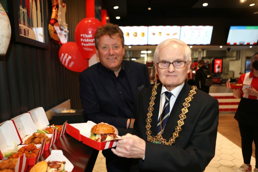 Lord Provost Borthwick, right, tries a burger with Fridays CEO Robert B Cook, left.