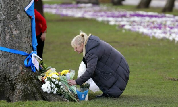 A family friend lays flowers at William's grave