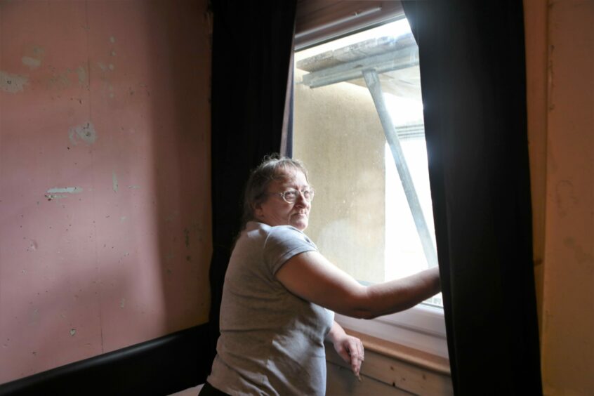 Donna Martin, 59, with her replacement window, which was installed nearly four months after the fire.