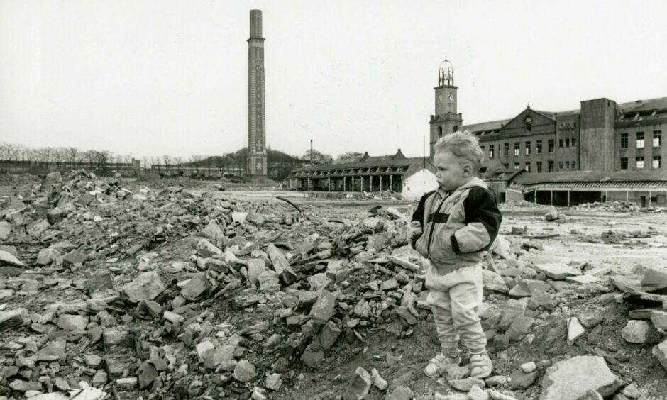 A young boy stands amid the rubble of jute buildings which used to make up Camperdown Works.