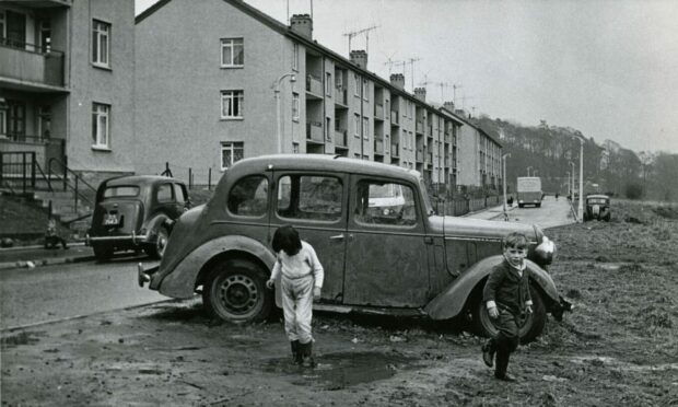 Children enjoying a splash in muddy puddles in Findale Street in 1963.