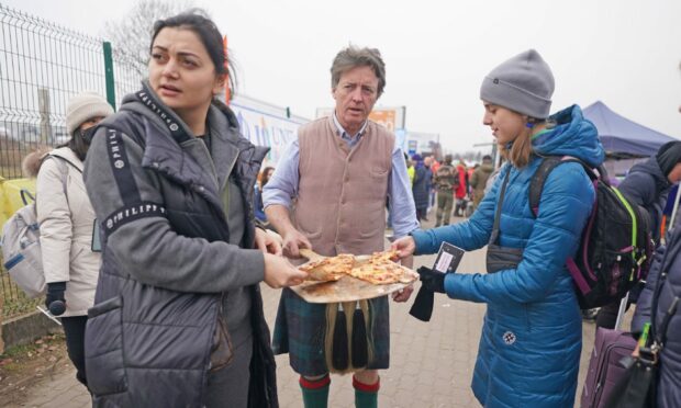 David Fox-Pitt, 57, from Loch Tay in Perthshire, hands out pizza to people crossing the border point from Ukraine into Medyka, Poland
