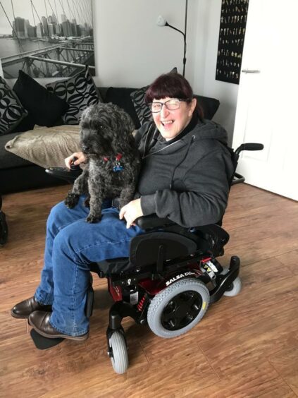 Petra Ryce shown in her wheelchair holding Sasha the dog.