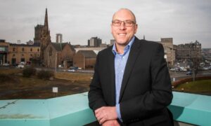 David Littlejohn standing on rooftop with Perth skyline behind