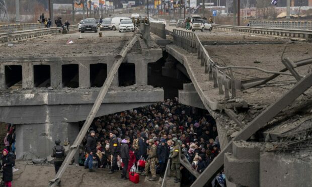 Ukrainians crowd under a destroyed bridge as they try to flee crossing the Irpin river in the outskirts of Kyiv, Ukraine. AP Photo/Emilio Morenatti.