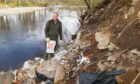 Robert Kellie attempts to clear up the landfill waste at the River Ericht. Photo: Paul Reid