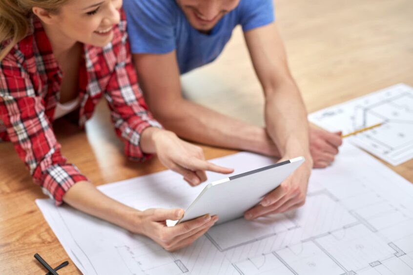 A photo of a couple looking at drawings for a house renovation