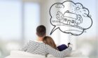 Photo from Shutterstock of couple sat on sofa thinking about their dream house