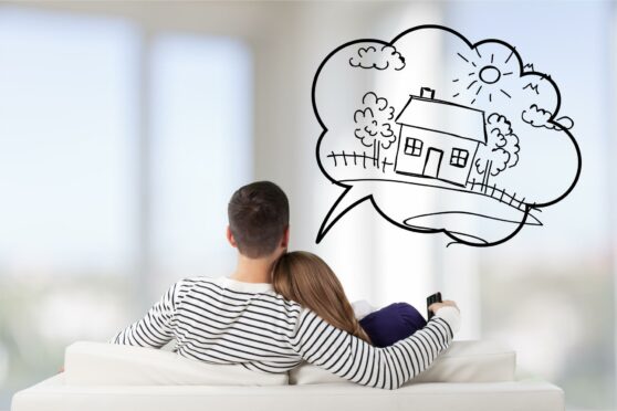 Photo from Shutterstock of couple sat on sofa thinking about their dream house