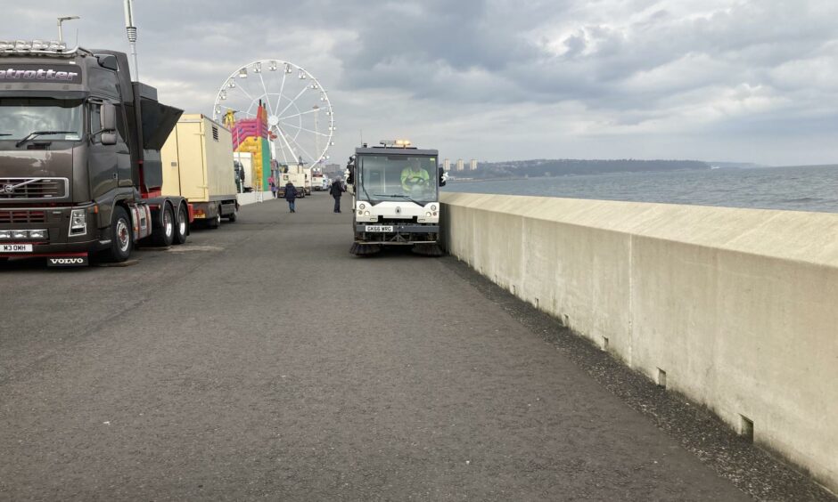 Cleaning the Esplanade, as throngs of people enjoy the Links Market just metres away.