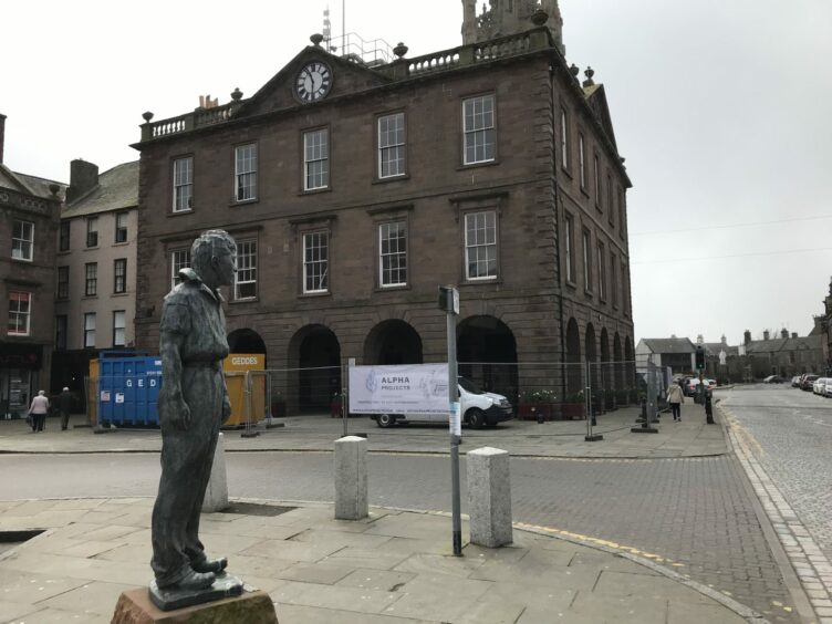 A statue of the William Lamb sculpture 'Bill the Smith' stands beside Montrose Town House.