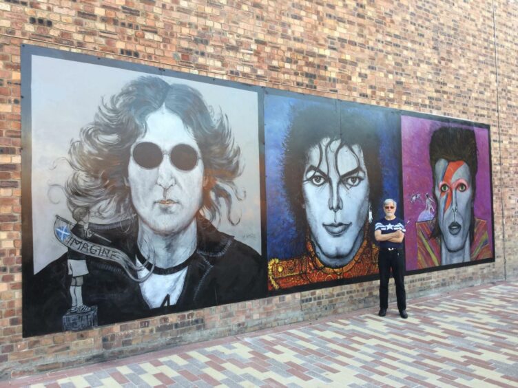 Ian Imrie standing next to large painting depicting John Lennon, Michael Jackson and David Bowie