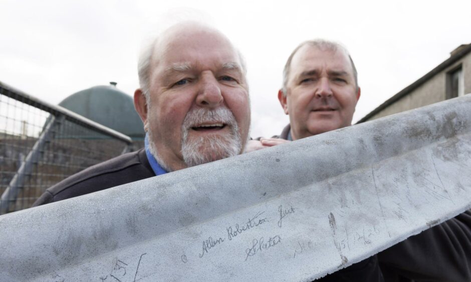 Allan Robertson Snr and Jnr with a roof ridge bearing the signatures of their predecessors.