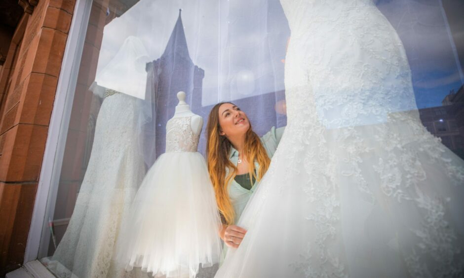 Tanith Johnston in the shop front window fixing a floral wedding dress.