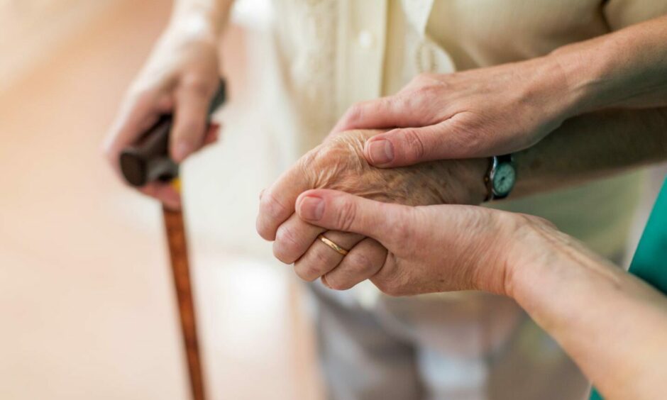Carer holding hand of elderly patient