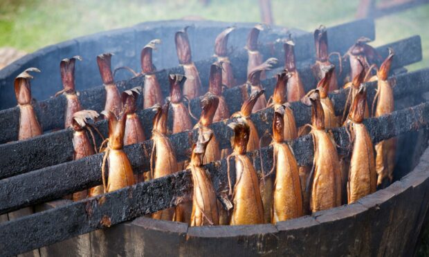 Traditional Scottish smoked fish cooking in wooden barrel.