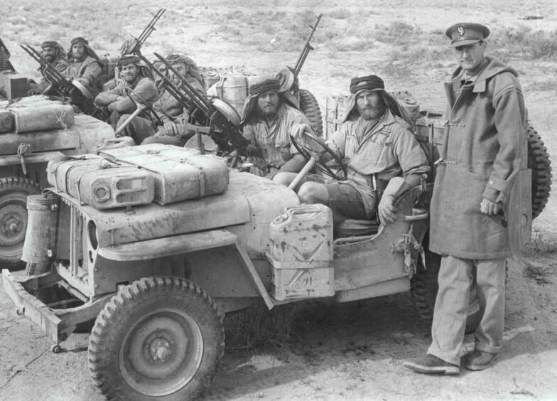 David Stirling standing next to men in jeeps, in a picture taken shortly before his capture in 1943.