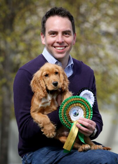 Photo shows Maurice Golden holding a young cocker spaniel and a rosette.