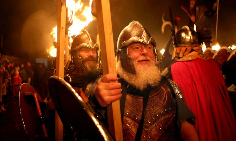 photo shows bearded members of the Jarl Squad at the Up Helly Aa festival in Lerwick walking with flaming torches