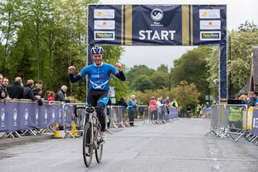 Picture shows a man in a blue jersey cycling over the finish line at Etape Caledonia.