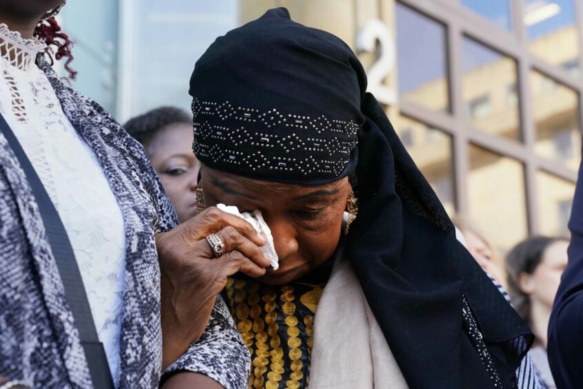 Sheku's mother Aminata Bayoh wipes away tears.