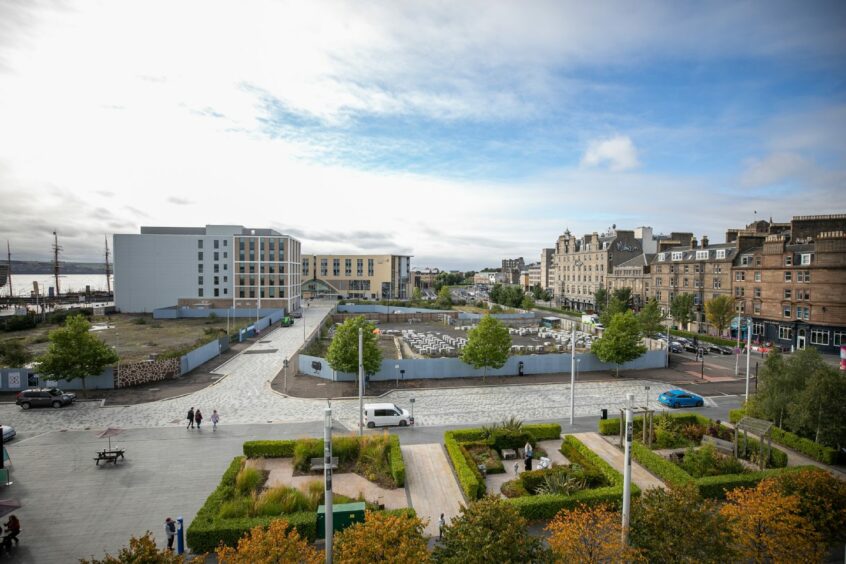 Photo is an aerial view of Dundee looking across Slessor gardens to the V&A Dundee, the Tay, the railway station and the city centre.