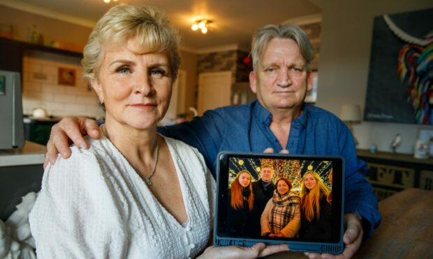 Sally and John Jenkins with a photograph of the Ukrainian family they are trying to help.