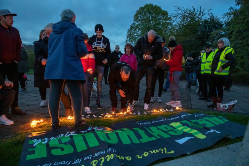 photo shows people laying tea light candles on the ground at the annual Darkness Into Light walk in Perth.
