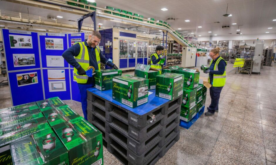 Workers pack bottles into boxes.