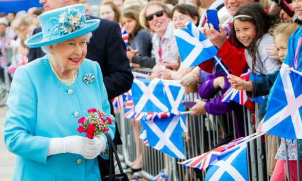 The Queen receiving flowers from members of the crowd at Slessor Gardens, Dundee, in 2016.