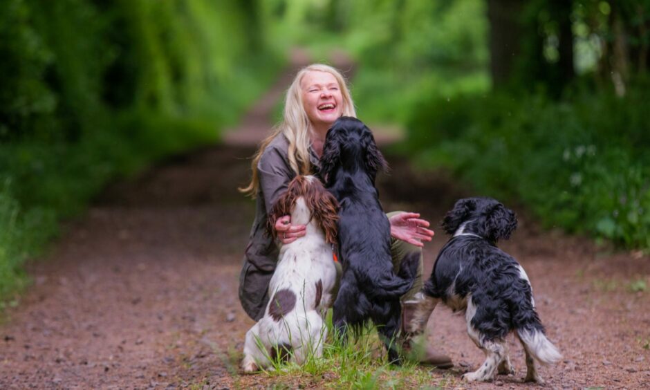 Wendy McArthur smiling as she is ambushed by spaniels.