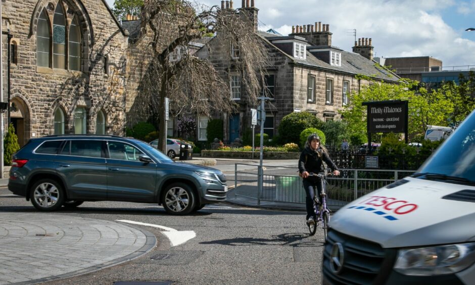 A cyclist traversing a busy St Andrews roundabout.