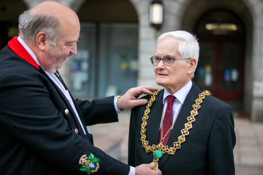 Council officer Ray Marra takes the chain from Lord Provost Ian Borthwick for the final time.